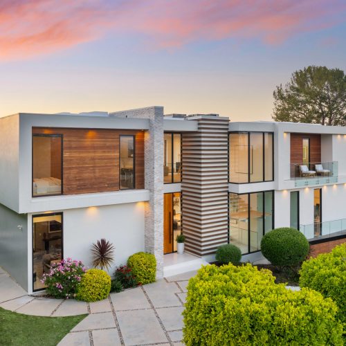 A Contemporary two-level home on hillside with shrubs and trees